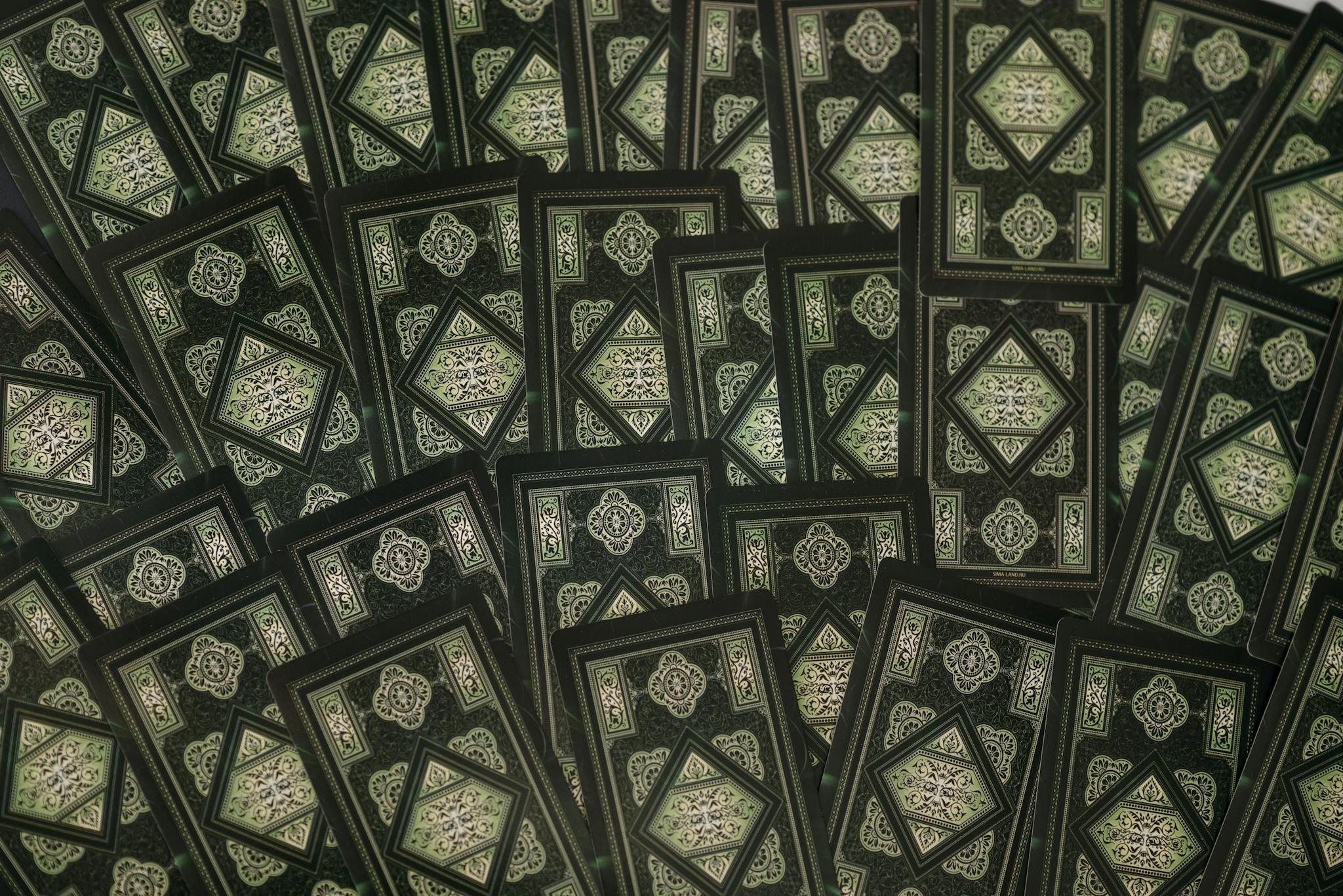 A flatlay of tarot cards with intricate green patterns, perfect for esoteric and fortune-telling themes.