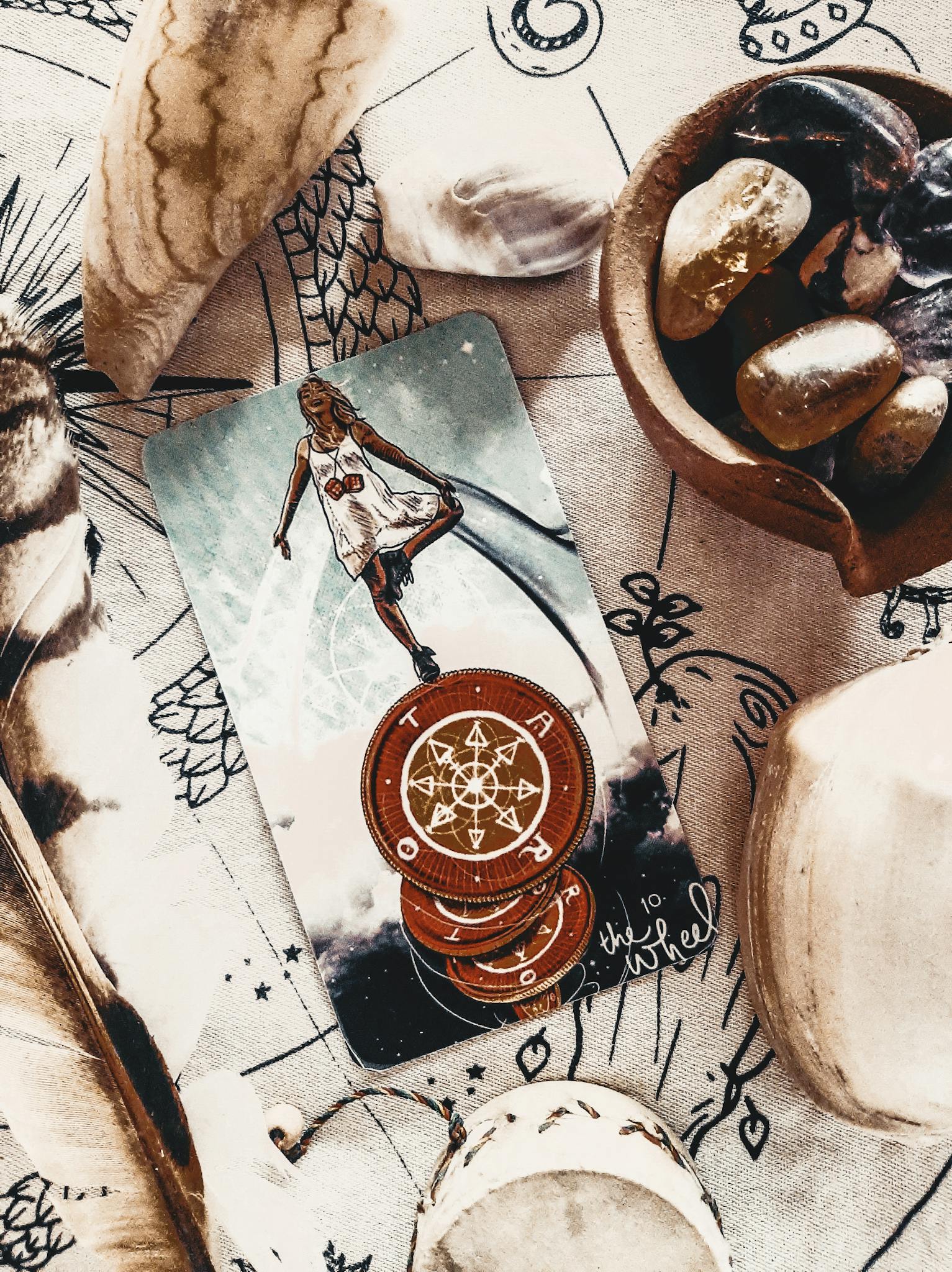 Close-up of a mystical tarot card with stones and feathers, evoking a magical atmosphere.