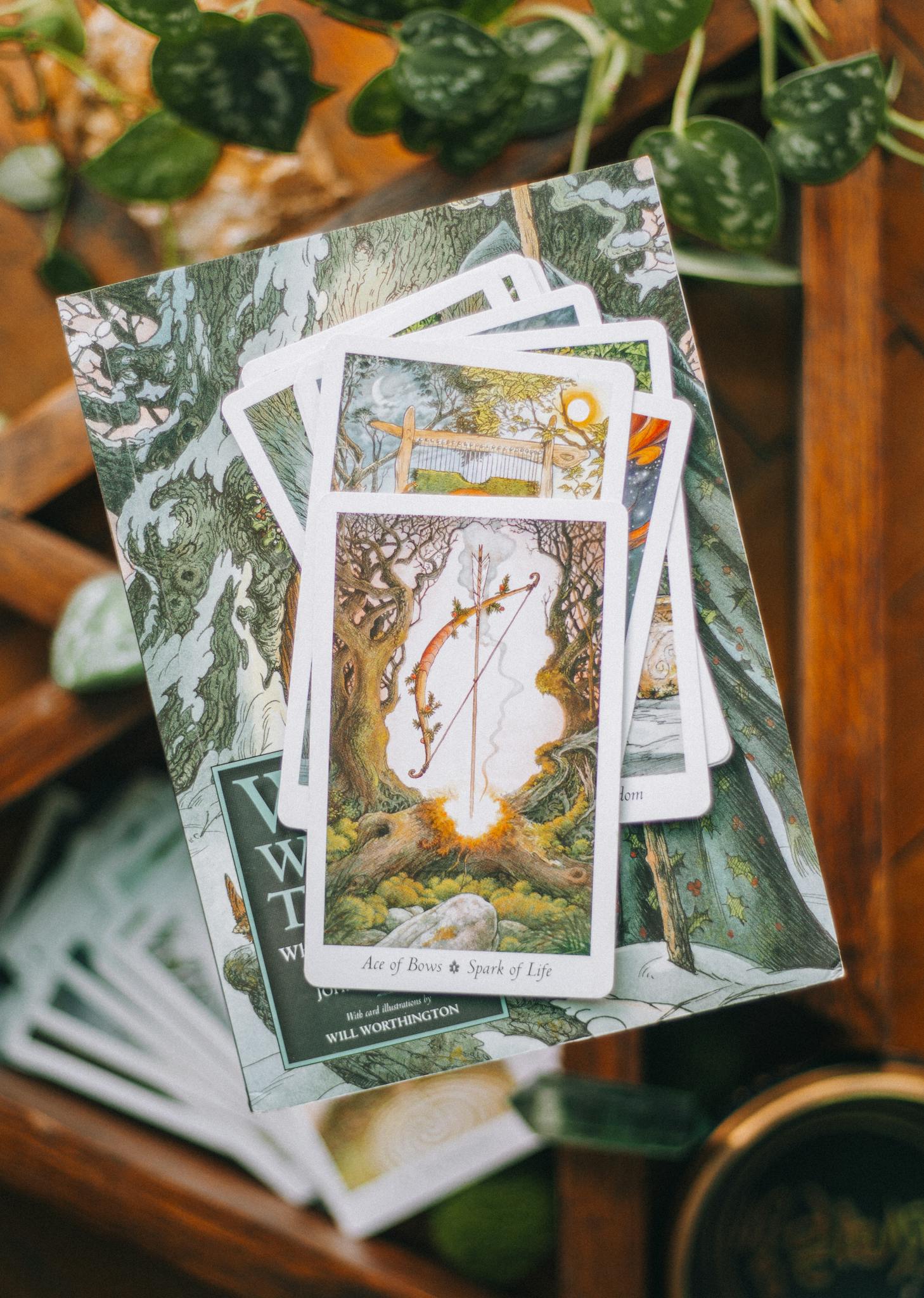 Tarot cards in a forest-themed deck on a wooden surface with leaves.